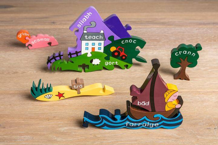 Colorful wooden puzzle pieces with Irish words depicting a mountain, house, tree, and boat on a light wood surface.