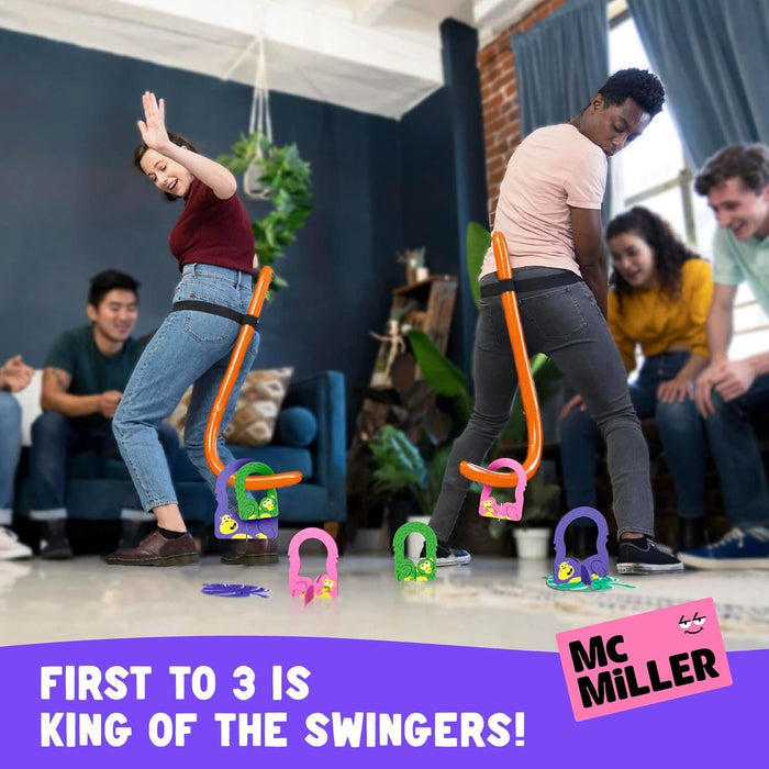 Two people wearing orange monkey tails on their waists swing to hook colorful plastic monkeys off the floor.