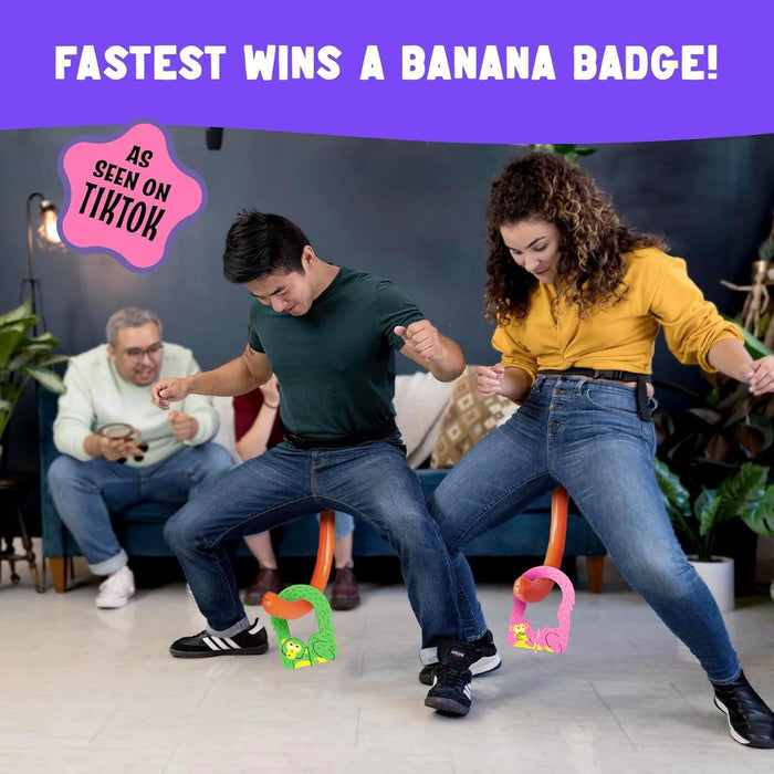 Two people wearing orange inflatable tails compete to hook green and pink monkey hoops in a fun party game.