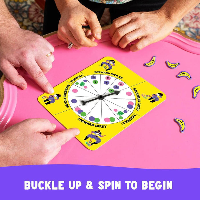 Hands surround a yellow game spinner and blue banana-shaped tokens on a bright pink circular board.