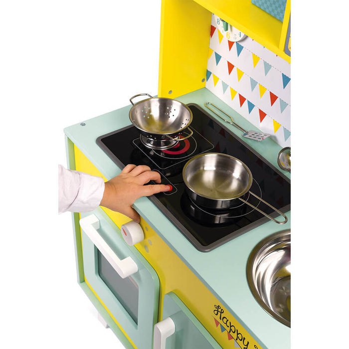 Child's hand on a mint and yellow toy stovetop with silver pots, glowing red burner, and colorful bunting backdrop.