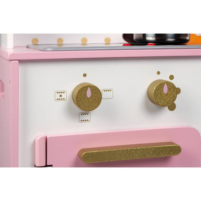 Pink and white wooden toy kitchen featuring two gold glittery control knobs and a glittery gold oven door handle.