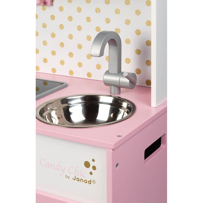 Close-up of a pink toy kitchen showing a silver sink and faucet against a gold polka dot backsplash.