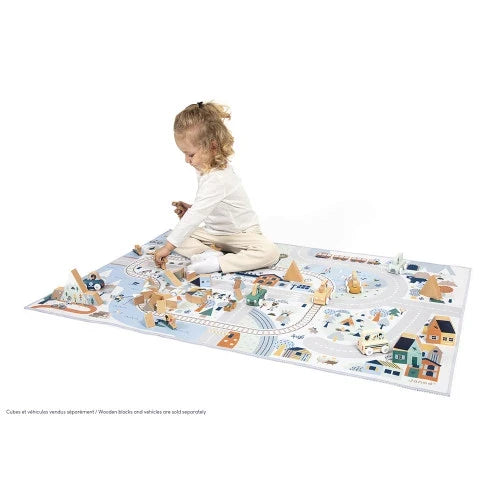 Child plays on a large winter-themed mountain valley mat featuring roads, tracks, and wooden toy blocks.