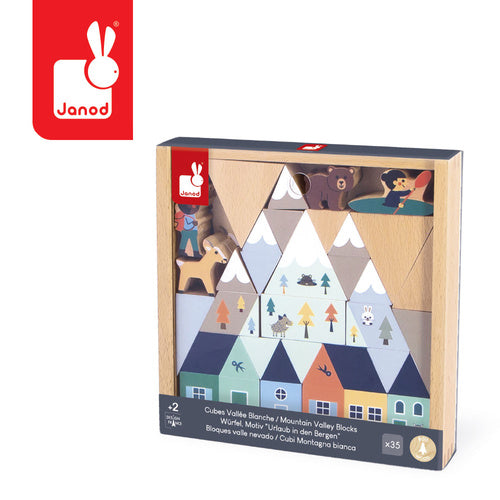 Wooden building blocks with snow-capped mountains, colorful houses, and animal figures in a square wooden tray.