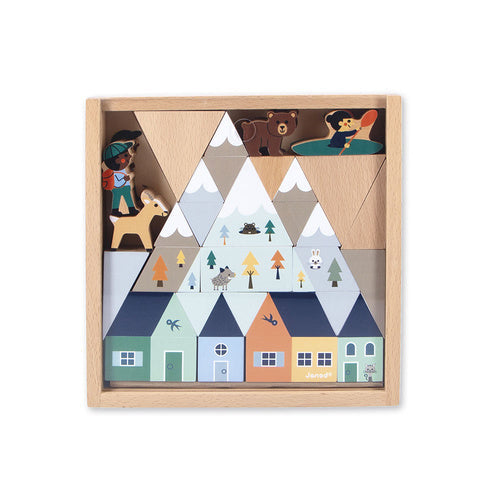 Mountain-themed wooden block puzzle in a square frame featuring houses, snowy peaks, animals, and a hiker.