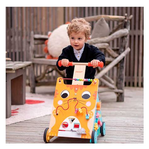 Toddler pushing an orange wooden cat-shaped walker with a bead maze and activity toys on a wooden deck.