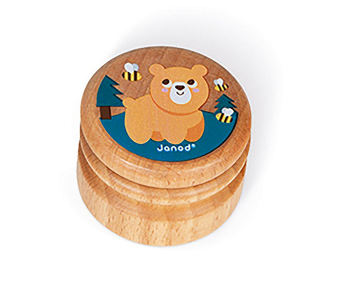 Small round wooden box featuring an illustration of a bear, bees, and trees on a teal top with Janod branding.