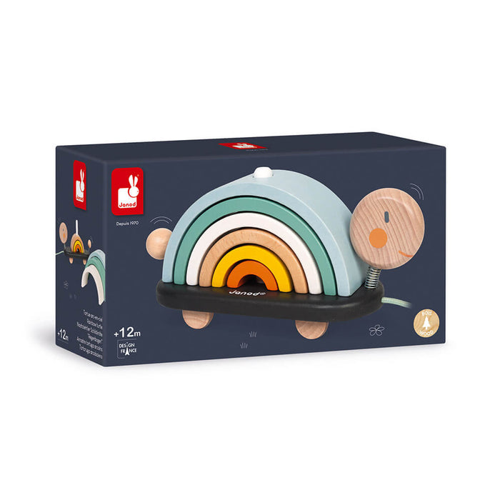 Wooden turtle pull toy with five colorful stacking arches on its back, shown in its dark blue retail box.