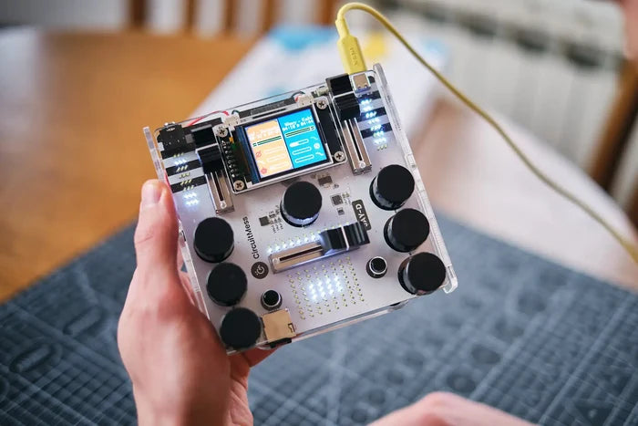 Handheld DIY DJ mixer with a clear case, color screen, black knobs, sliders, and glowing white LEDs.