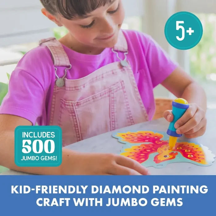 Girl in pink overalls uses a blue applicator to place yellow gems on a butterfly. Text: 500 jumbo gems, ages 5+.