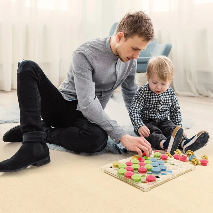 A man and toddler play with a clear pegboard and colorful mushroom-shaped pegs on a light wooden floor.