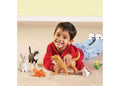 Smiling boy with large toy animals: tan dog, tuxedo cat, grey rabbit, orange goldfish, guinea pig, and green parakeet.