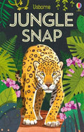 Spotted yellow leopard walking forward through green jungle leaves and pink flowers on a dark card game box.