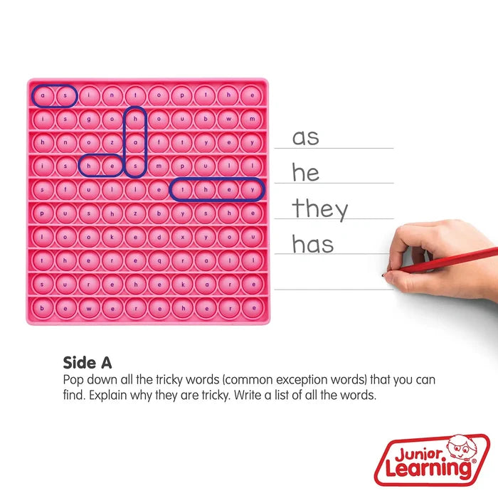 Pink silicone bubble board with letters and circled words beside a hand writing on paper.