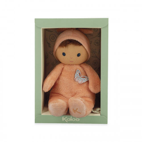 Soft peach plush baby doll with a butterfly patch in a green Kaloo display box.