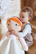 Large plush doll with orange hair, blue eyes, and a starry white dress being hugged by a toddler.