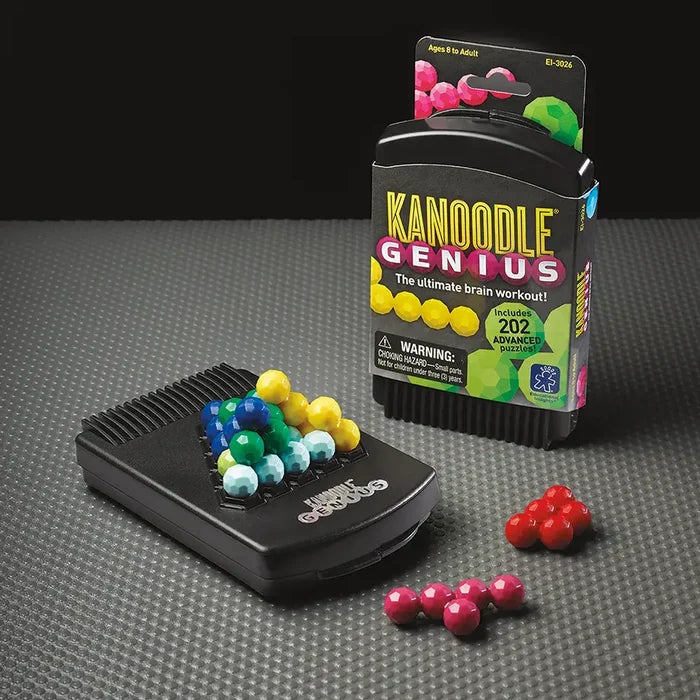 Colorful faceted bead pieces forming a 3D pyramid on a black Kanoodle Genius game case next to its packaging.