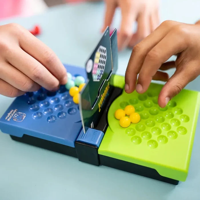 Hands playing a puzzle game with blue and lime green boards, colorful bead pieces, and a central challenge card.