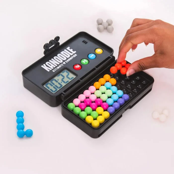 Hand placing an orange bead piece into a black puzzle game with a digital timer and various colorful bead shapes.