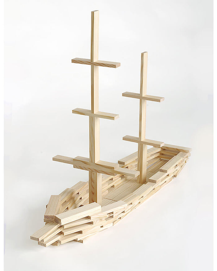 Model sailing ship built from light-colored natural wood planks, featuring two tall masts and a layered hull.