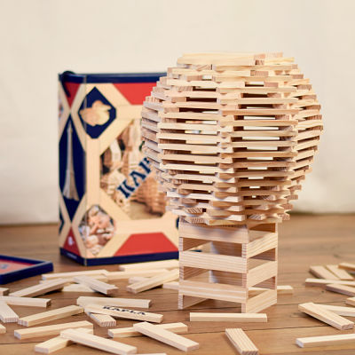 Light wood planks built into a sphere on a stand next to a storage box and scattered pieces on a wooden floor.