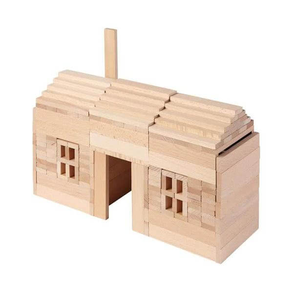 Model house built from light natural wooden planks with a stepped roof, two window frames, and a tall chimney.