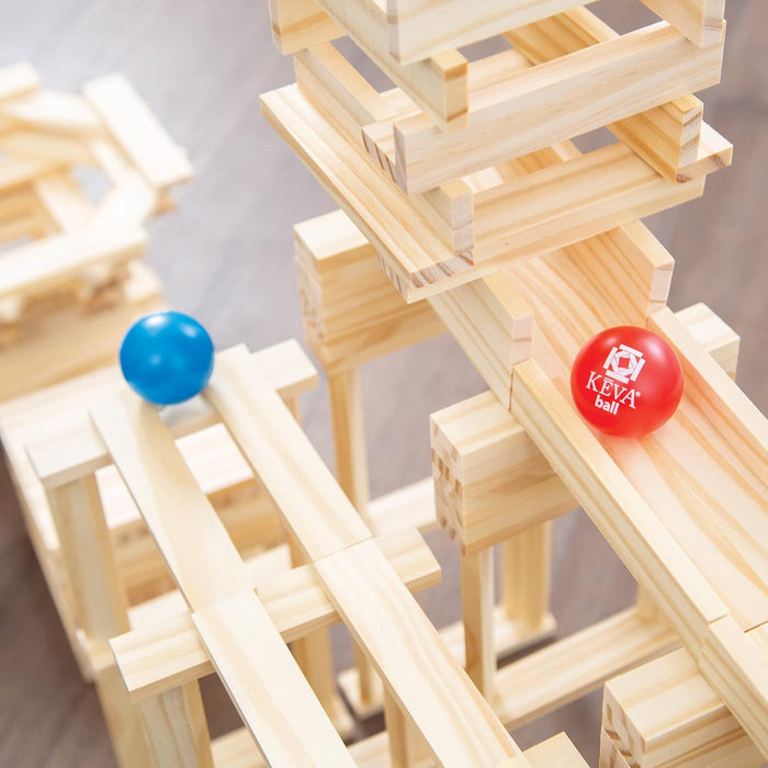 A red ball and a blue ball resting on a tiered track structure made of light-colored wooden building planks.