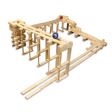 Elaborate marble run structure built from light wood planks with blue and red marbles on a multi-level track.