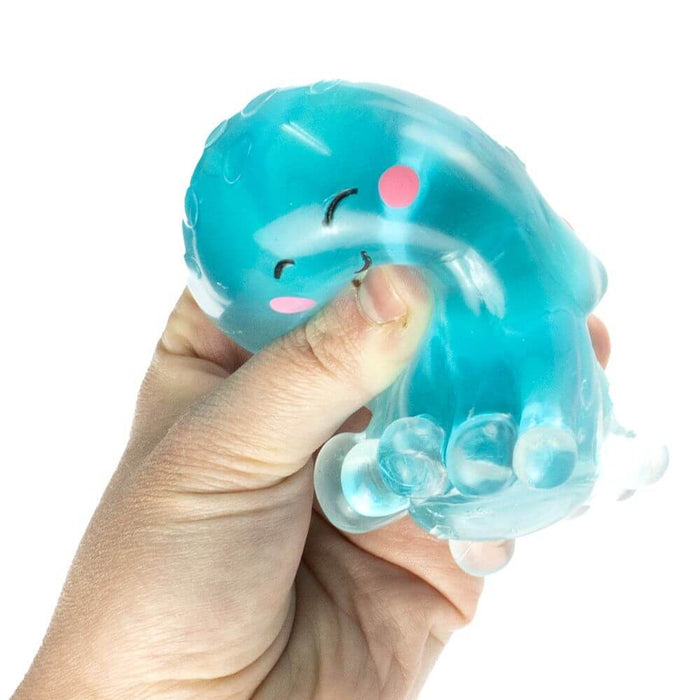 Hand squeezing a translucent blue squishy octopus toy with pink cheeks and small clear beads inside.
