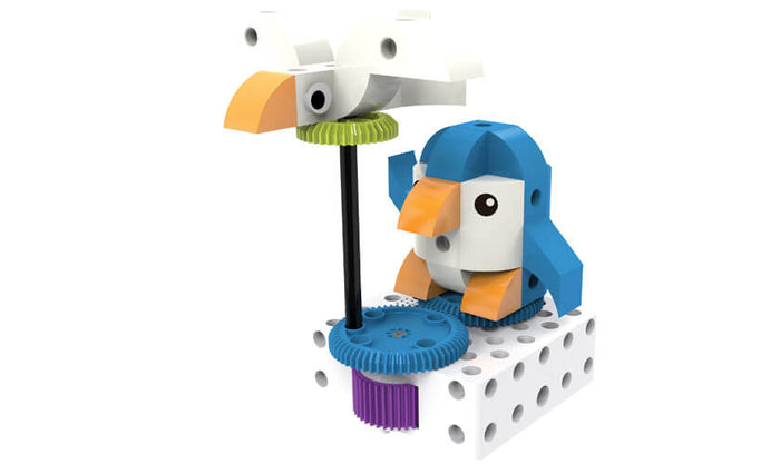 Toy with a white bird on a pole and blue penguin on gears, with orange beaks and a white building block base.