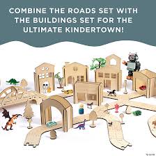 Interlocking light wood toy road tracks, bridge, and buildings with plastic dinosaur and robot figures.
