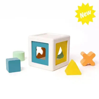 White cube with blue and yellow cutout sides and colorful blocks including a blue square and orange cross.