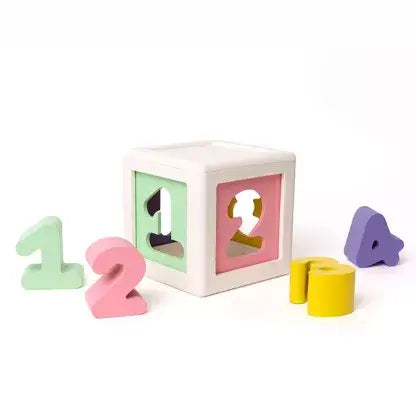 White shape-sorting cube with pastel panels and colored foam numbers 1 to 4 on a plain white background.