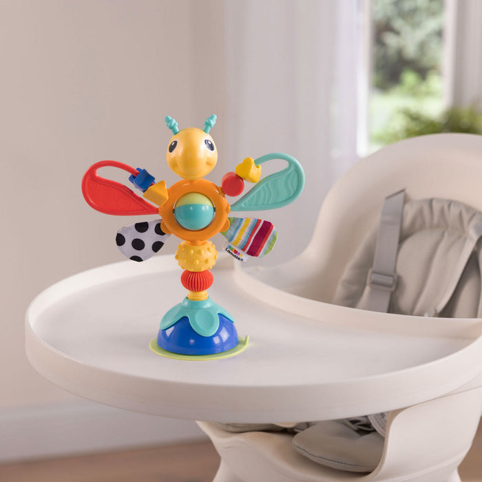 Colorful suction-base bug toy with textured wings and a spinning ball center, shown on a white high chair tray.