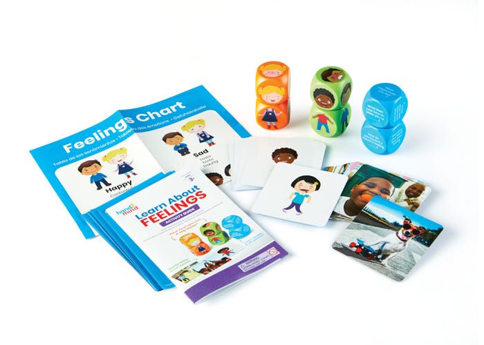 Educational set with blue booklets, character cards, photo cards, and colorful cubes featuring children's faces.