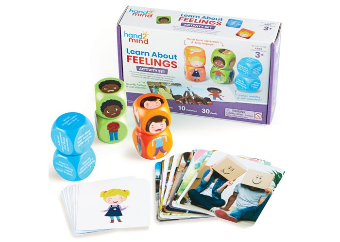 Purple toy box with six green, orange, and blue cubes showing faces and text, and sets of activity cards.