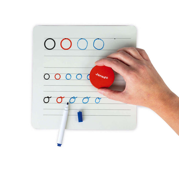 Hand using a red magnetic tool on a white dry-erase board with circle patterns, a marker, and a small blue eraser.