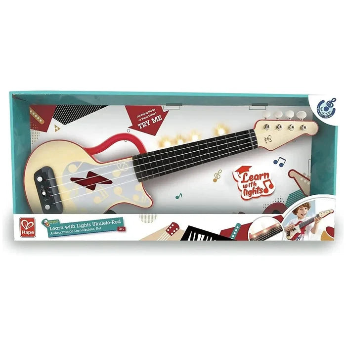 Red and cream toy ukulele in a teal box featuring a light-up fretboard, music notes, and a built-in handle.