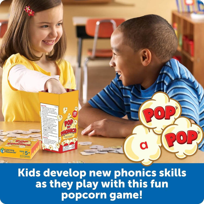 Two children playing Pop for Phonics, a card game with a yellow popcorn-shaped box and round white cards.