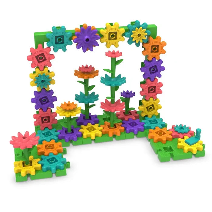 Colorful gear building set featuring floral stems, leaves, and a hand crank on green interlocking baseplates.