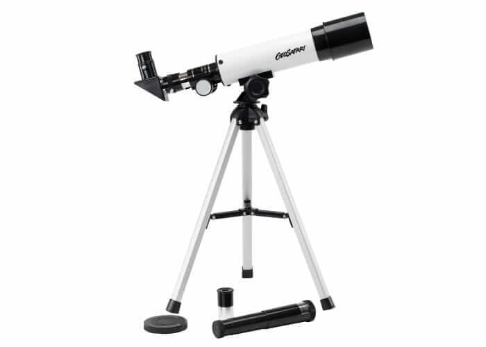 White telescope with black trim on a silver tabletop tripod, plus extra eyepieces and a lens cap shown below.
