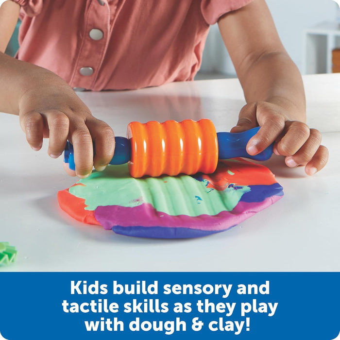 Child uses an orange textured roller with blue handles on colorful dough. Text: Kids build sensory and tactile skills.