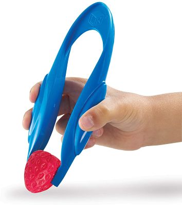 Child’s hand using large blue plastic tweezers to grasp a small red textured toy strawberry.