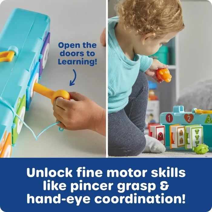 A child uses a yellow plastic key to unlock numbered doors on a blue toy house, revealing colorful hidden characters.