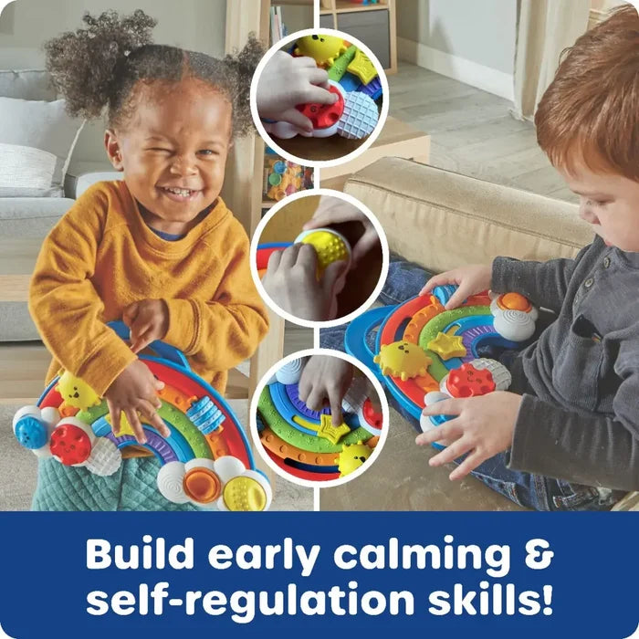 Two children play with a colorful rainbow sensory board featuring tactile sliders, dials, and textured buttons.