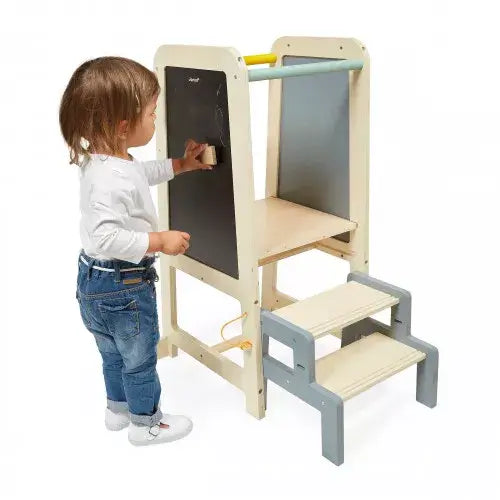 Wooden activity tower with gray steps and a chalkboard. A child stands beside it, drawing on the black panel.
