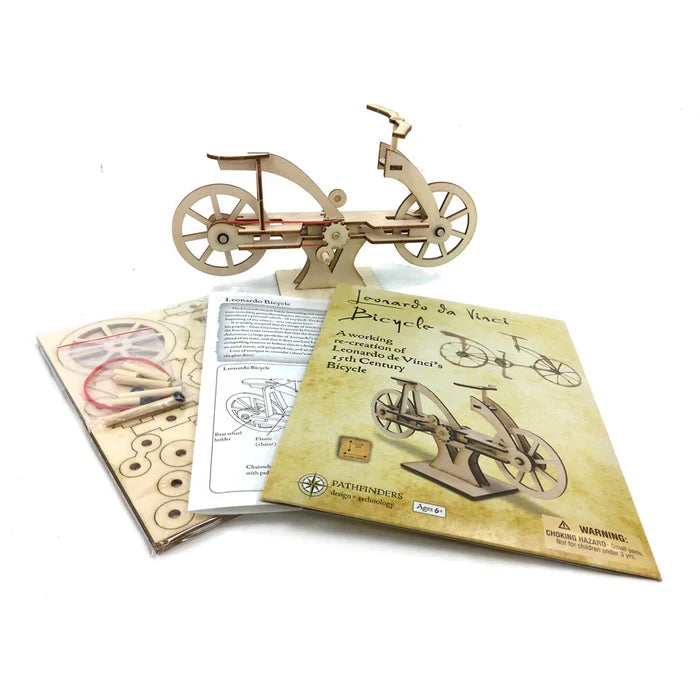 Assembled light-wood bicycle model with spoked wheels, instruction manual, and flat-packed laser-cut wood pieces.