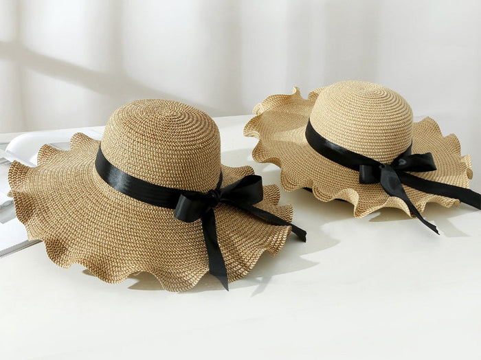 Light brown women's straw sun hat with wide brim, floppy derby style for summer beach and outdoor wear.
