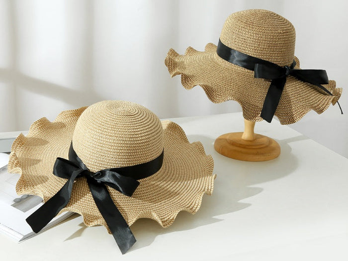 Light brown women's straw sun hat with wide brim, floppy derby style for summer beach and outdoor wear.